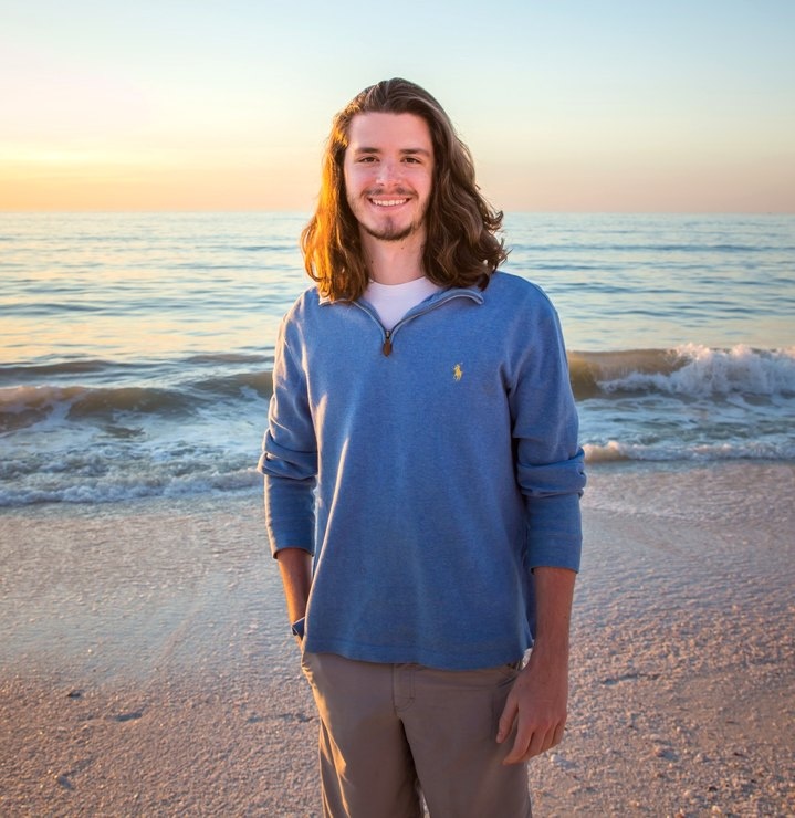 Colin standing on a beach at sunset